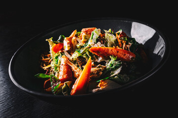 Chicken, carrot, lettice and tomato salad on black plate