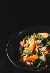Chicken, carrot, lettice and tomato salad on black plate