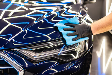 A man cleaning car with cloth, car detailing (or valeting) concept. Selective focus.