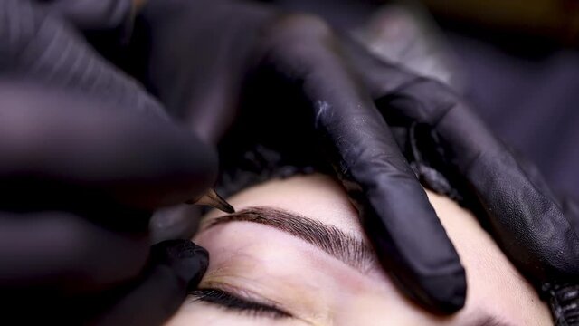 close-up eyebrow tattooing procedure by a master stretches the eyebrows 