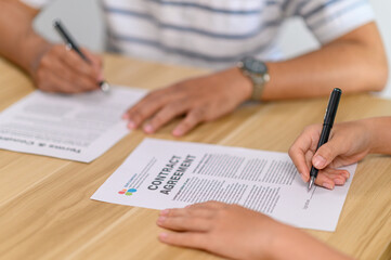 Male and female employees sign a contract together.