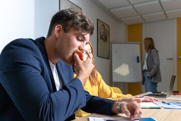 Young boy eating an organic apple at a work meeting