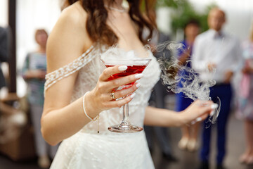 Glass of champagne with dry ice in the bride's hand