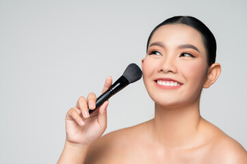 Portrait of Beautiful Asian woman holding makeup blusher brush