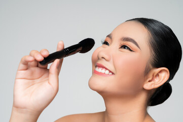 Portrait of Beautiful Asian woman holding makeup blusher brush