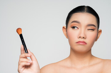 Portrait of Beautiful Asian woman holding makeup blusher brush