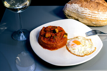 Plate of vegetable ratatouille, accompanied with rustic bread and a glass of wine, traditional food from Spain