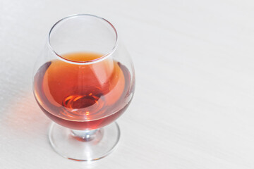 A glass of cognac or brandy on a light background. Empty space for the copy space on the right