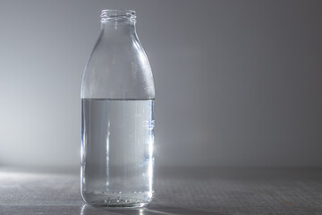 Glass water bottle on a gray background. copy space