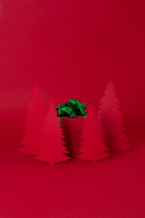 Christmas creative concept. Red Christmas tree of paper with red gift on the red background. Holiday concept.