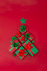 Christmas creative concept. Christmas tree made of different small and big gift boxes on the red background. Holiday concept.