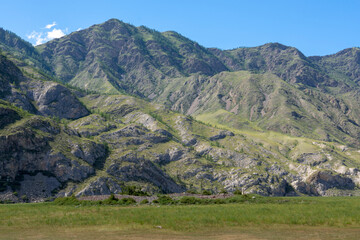 peaks of mountains against a blue sky with white clouds. Summer clear sunny day