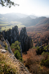 Scenic landscape in Sulov, Slovakia, on beautiful autumn sunrise with colorful leaves on trees in forest and bizarre pointy rocks on mountains and slight