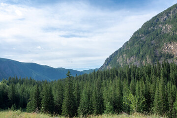 peaks of mountains against a blue sky with white clouds. Summer clear sunny day