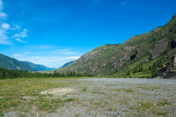 peaks of mountains against the sky with white clouds. Summer sunny day. Mountain asphalt road
