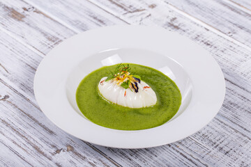 Green sauce with poached egg in white plate