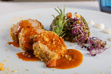 Rollè di maiale tagliato a pezzi condito con tarallo sbriciolato, salsa e con contorno di scarole servito in un ristorante