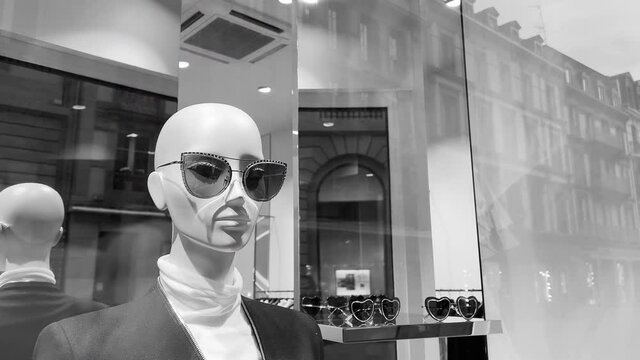 Fashionable mannequin in showcase window of a modern store with reflection of passing tramway - black and white 4k UHD footage