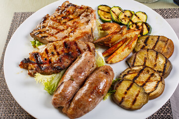Misto di carne servito in un ristorante con verdure grigliate, patate al forno e insalata