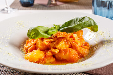 Interiora di maiale cotte con patate e sugo di pomodoro con basilico per decorazione servite in un ristorante
