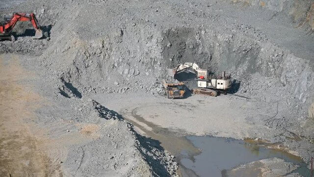 Russia, Amur region, July 7, 2021. Quarry, open pit mining, gold ore mining. The ore is loaded by a Liebherr excavator into a Caterpillar truck from the quarry. Summer.