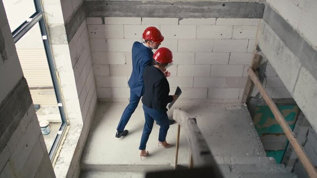 Caucasian male and female architects walking and supervising on construction site. Shot with RED helium camera in 8K     