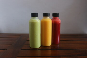 Avocado, mango, strawberry juice served in plastic bottles with black lids

