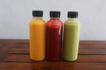 Avocado, mango, strawberry juice served in plastic bottles with black lids

