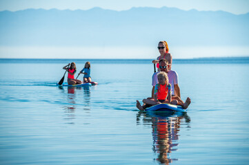 Happy Family on SUP stand up paddle on vacation. - obrazy, fototapety, plakaty