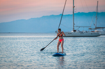 Woman riding SUP stand up paddle on vacation.