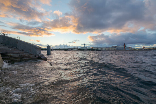 Raised water level in the Neva River due to strong winds. Arrow of Vasilievsky Island and Rastral Columns in the background. Beautiful clouds in the sunset sky. Saint-Petersburg, Russia.