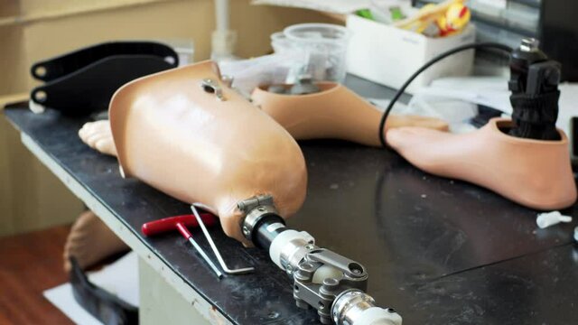Close view of artificial bionic high technology legs and feet prosthesis on the table in clinic. Laboratory of medical prosthetics technician and his tools on the table