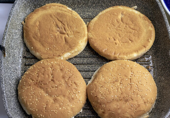 The burger bun is heated in a grill pan.