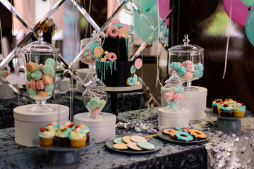 Chocolate cake with black glaze and sweets on a candy bar