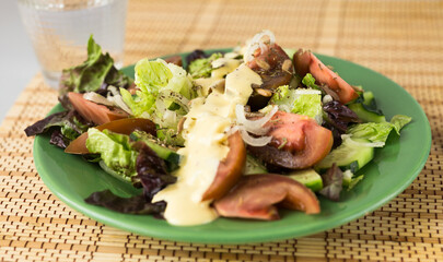 vegetable salad of greens, tomatoes and cucumbers on a green plate