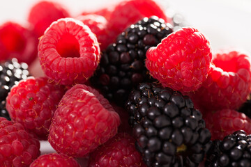 handful of raspberry and blackberry berries on white background