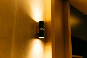 Warm black lamp on a beautiful wooden wall. Indirect light. - obrazy, fototapety, plakaty