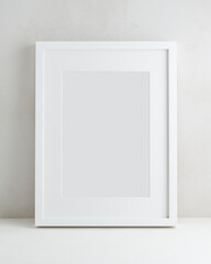 Empty white frame with passe-partout on the background of a light wall. Mock up poster with a place...
