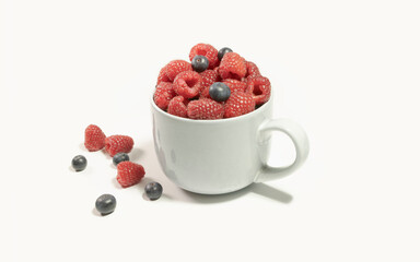 Raspberries and blueberries in a large gray cup on a white background