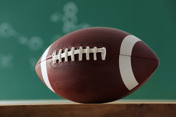 American football ball against blurred game scheme