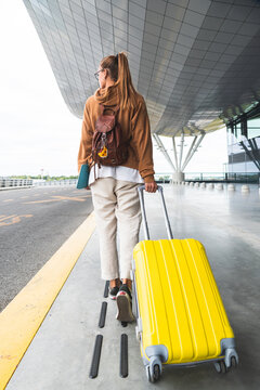 Woman with wheeled luggage walking at airport