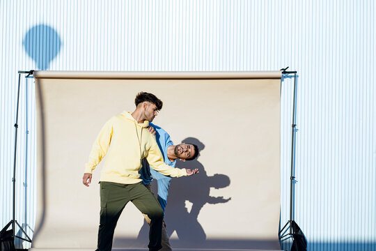 Male dancer friends performing together in front of backdrop