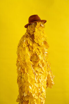 Woman with hat and autumn leaf costume by yellow background