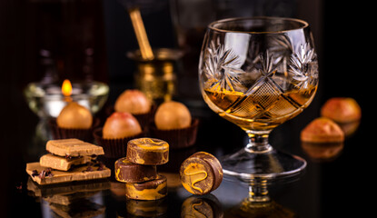 still life with chocolate pralines and a glass of alcohol