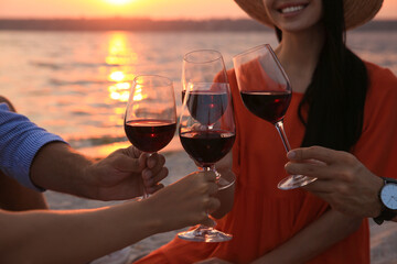 Group of friends having picnic near river at sunset, closeup