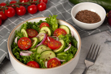 Vegetable salad with cucumber, tomato, onion, green salad and linseed seeds. Close up photo of...