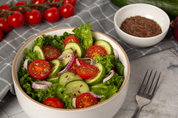 Vegetable salad with cucumber, tomato, onion, green salad and linseed seeds. Close up photo of healthy food