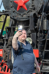 a 30-year-old man takes a selfie against the steam locomotive