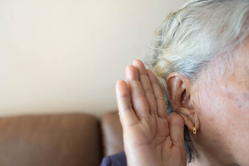 Hearing loss in seniors (Presbycusis) concept. Close up of elderly woman holding her hand near ear...