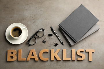 Word Blacklist of wooden letters, cup with coffee and office stationery on grey table, flat lay